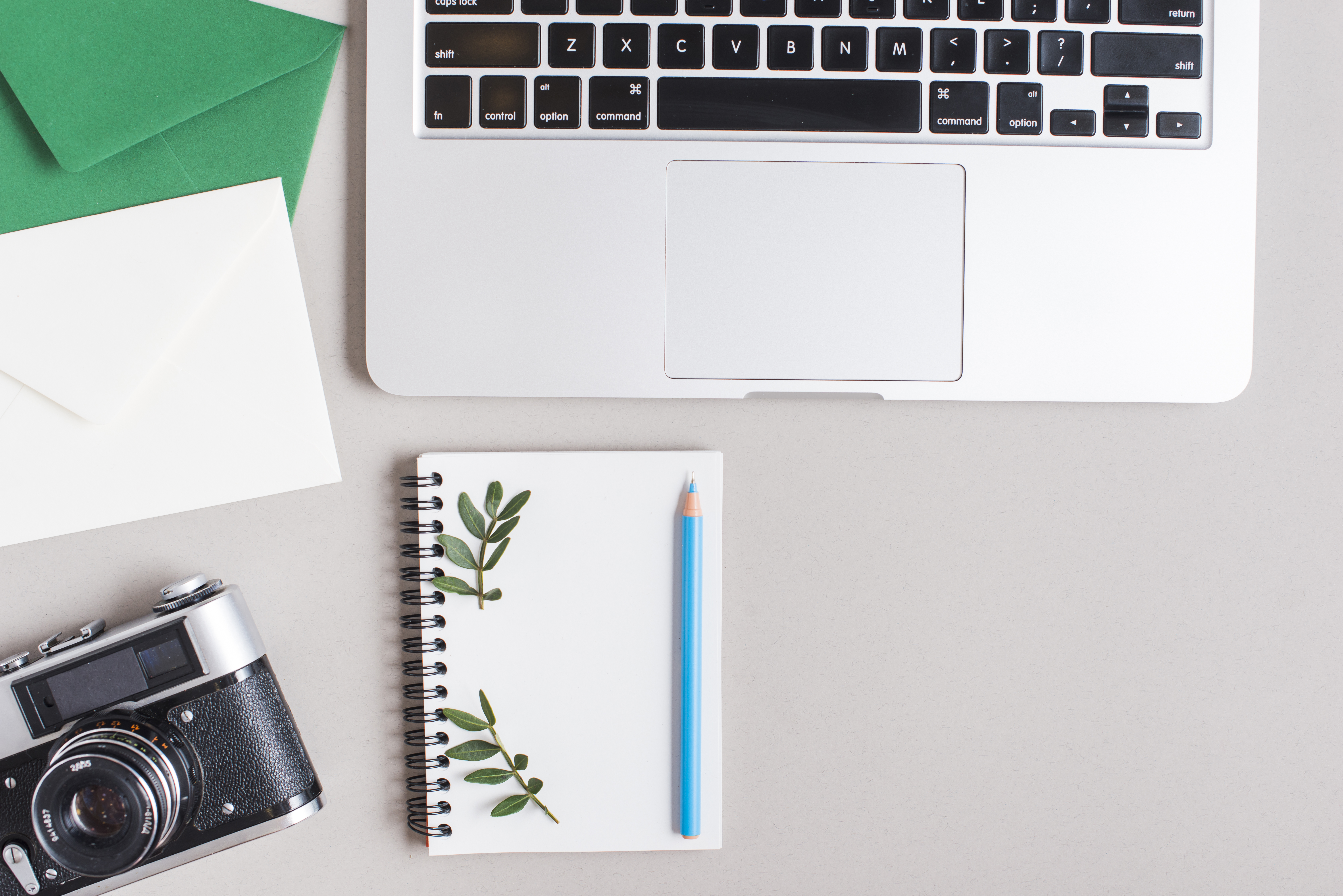 A working desk with a notebook, camera, and laptop.